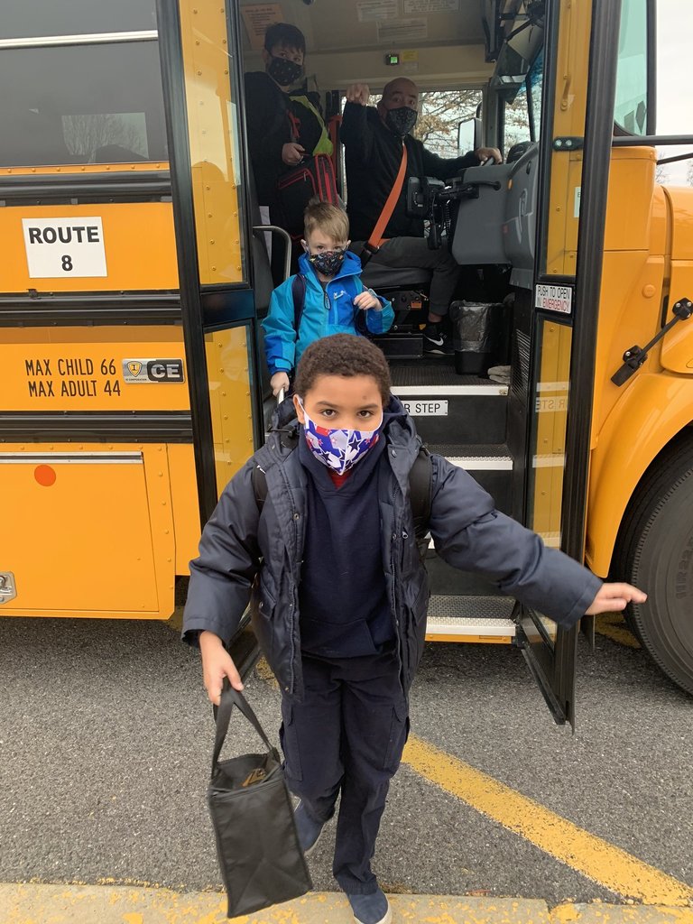 MES student in face mask and black jacket exiting school bus